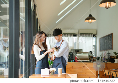 Small business owners enjoying time with a cat in their pet-friendly coffee shop 125630282
