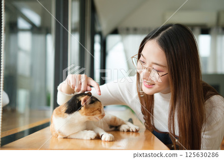 Small business owners enjoying time with a cat in their pet-friendly coffee shop Small business owners enjoying time with a cat in their pet-friendly coffee shop 125630286