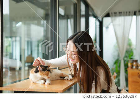 Small business owners enjoying time with a cat in their pet-friendly coffee shop Small business owners enjoying time with a cat in their pet-friendly coffee shop 125630287