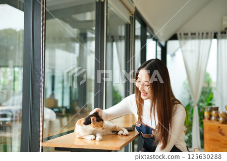 Small business owners enjoying time with a cat in their pet-friendly coffee shop Small business owners enjoying time with a cat in their pet-friendly coffee shop 125630288