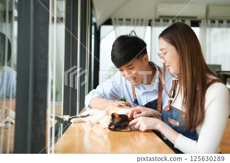 Small business owners enjoying time with a cat in their pet-friendly coffee shop 125630289