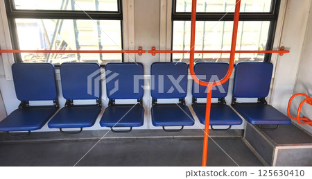 Empty carriage with blue seats of a city or intercity electric train. City transport, carriage interior.  125630410
