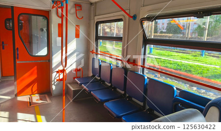 Interior of an empty city train carriage with blue seats and orange handrails. Passenger train. Empty seats in the carriage. Intercity. Interior of an empty city train carriage with blue seats and orange handrails. Passenger train. Empty seats in the carriage. Intercity. 125630422