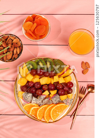 Fruit salad with kiwi, mango, dragon fruit, grapes, nuts, citrus fruits with chia seeds for weight loss and a glass of orange juice. Natural nutrition and detox diet concept, Healthy breakfast with 125630797