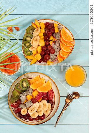 Kitchen background with fruit salads from dragon fruit, mango, kiwi, orange, nuts, dried apricots and orange juice, exotic fruits for a healthy lifestyle, products for a detox diet and weight loss, 125630801