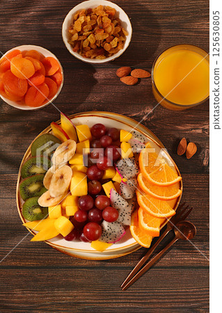 Fruit salad with kiwi, mango, dragon fruit, grapes, nuts, citrus fruits with chia seeds for weight loss and juice. Natural nutrition and detox diet concept, Healthy breakfast with ingredients, kitchen 125630805