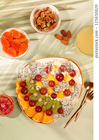Healthy light breakfast with ingredients. Fruit salad with soft grain cottage cheese, yogurt, dragon fruit, kiwi, mango, oranges, nuts, grapes, diet healthy lifestyle advertisement, kitchen background Healthy light breakfast with ingredients. Fruit salad with soft grain cottage cheese, yogurt, dragon fruit, kiwi, mango, oranges, nuts, grapes, diet healthy lifestyle advertisement, kitchen background 125630820