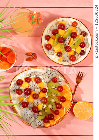 Kitchen background with fruit salads with soft grain cottage cheese, yogurt, dragon fruit, kiwi, mango, oranges, nuts, orange juice and grapes. Healthy light breakfast with ingredients, 125630824