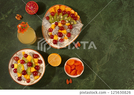 Kitchen background with fruit salads with soft grain cottage cheese, yogurt, dragon fruit, kiwi, mango, oranges, nuts, orange juice and grapes. Healthy light breakfast with ingredients, 125630826