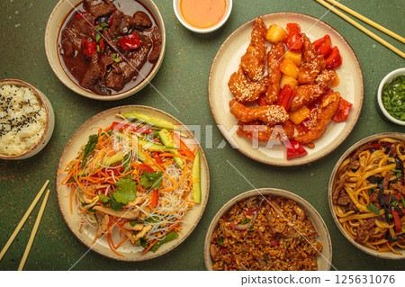 Variety of Chinese food dishes top view on table with chopsticks, rustic green background, cuisine of China 125631076