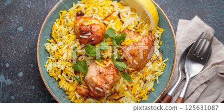 Traditional Indian dish chicken biryani with cilantro and lemon in a bowl top view on rustic background Traditional Indian dish chicken biryani with cilantro and lemon in a bowl top view on rustic background 125631087
