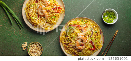 Two plates of thai noodles with shrimp and peanuts on green background, dish of Thailand Two plates of thai noodles with shrimp and peanuts on green background, dish of Thailand 125631091