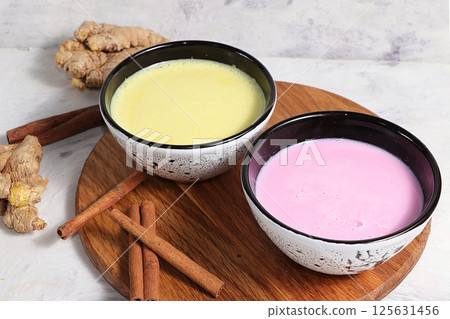 Turmeric latte and pink-golden milk for immunity, ginger and cinnamon on a gray table, helps fight viruses, has antioxidant properties, the concept of alternative medicine 125631456