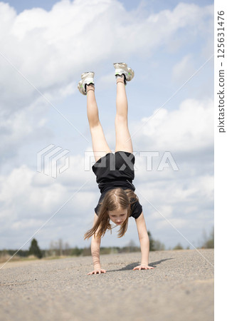 Little girl stands on her hands upside down 125631476