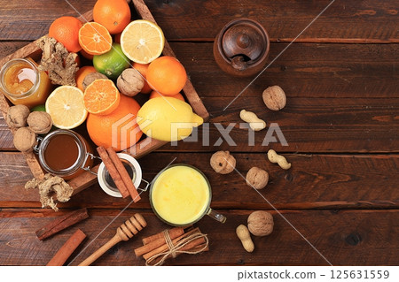 Healthy natural food for flu and colds. Golden turmeric latte and fresh fruit with vitamin C and natural ingredients to strengthen the immune system, protect against viruses, selective focus. Healthy natural food for flu and colds. Golden turmeric latte and fresh fruit with vitamin C and natural ingredients to strengthen the immune system, protect against viruses, selective focus. 125631559