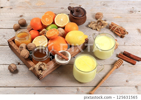 Healthy natural food for flu and colds. Golden turmeric latte and fresh fruit with vitamin C and natural ingredients to strengthen the immune system, protect against viruses, selective focus. 125631565