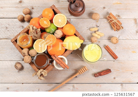 Healthy natural food for flu and colds. Golden turmeric latte and fresh fruit with vitamin C and natural ingredients to strengthen the immune system, protect against viruses, selective focus. 125631567