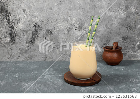 Fresh plain homemade herbal yogurt, kefir, ayran, lassi, smoothie in a glass with a paper bamboo tube on an old gray background with space for text. Probiotic fermented milk drink, natural diet food, 125631568