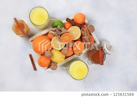 Traditional turmeric latte with ginger root, cinnamon sticks, honey and citrus fruits. Alternative medicine concept, anti-inflammatory, anti-virus, selective focus Traditional turmeric latte with ginger root, cinnamon sticks, honey and citrus fruits. Alternative medicine concept, anti-inflammatory, anti-virus, selective focus 125631569