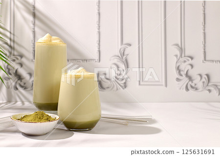 Green tea matcha latte with milk on elegant kitchen sunny background with palm leaves and matcha powder. Traditional Indian drink rich in antioxidants used for weight loss and treatment, 125631691