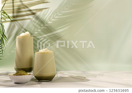 Green tea matcha latte with milk on elegant kitchen sunny background with palm leaves and matcha powder. Traditional Indian drink rich in antioxidants used for weight loss and treatment, 125631695