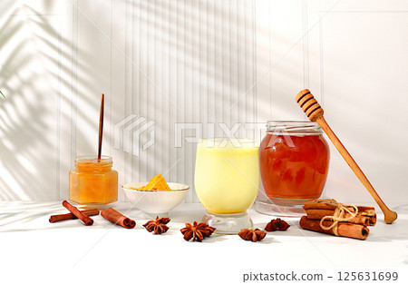 Golden turmeric latte with ginger, cinnamon, anise and honey spices on a sunny table. Weight loss and alternative medicine concept, immunity booster during pandemic, Indian cuisine advertisement 125631699