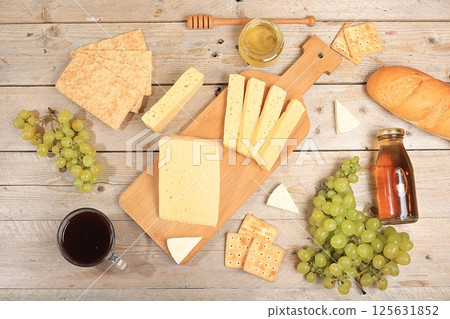 Assortment of different varieties of cheese, red wine, grapes and cracker, the basis of the French diet, healthy and natural food selection, advertising card or invitation to a cafe, shop, menu, Assortment of different varieties of cheese, red wine, grapes and cracker, the basis of the French diet, healthy and natural food selection, advertising card or invitation to a cafe, shop, menu, 125631852