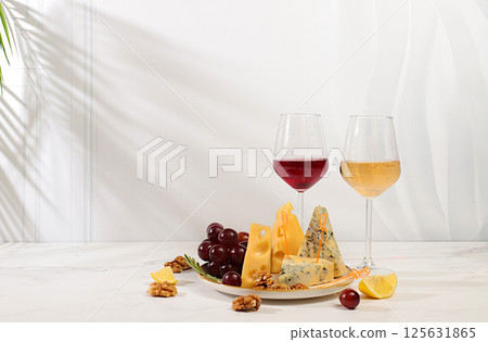 Wine tasting. Still life with gourmet blue cheese, parmesan, grapes, honey, nuts, rosemary and wine. Cheese plate with seasonal wine snacks, Italian cuisine concept, menu for restaurant and cafe. Wine tasting. Still life with gourmet blue cheese, parmesan, grapes, honey, nuts, rosemary and wine. Cheese plate with seasonal wine snacks, Italian cuisine concept, menu for restaurant and cafe. 125631865