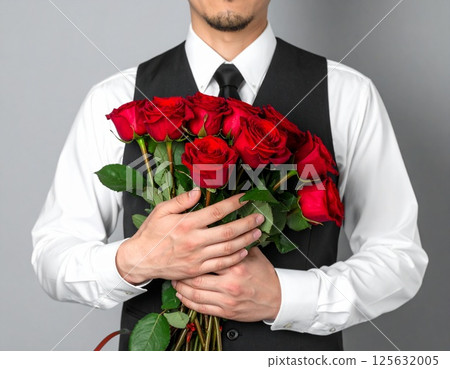 A man holding a bouquet of red roses on his chest 125632005