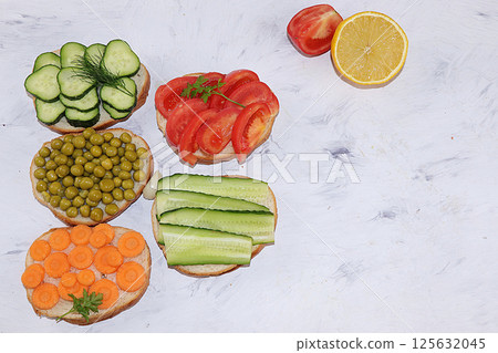 Fried bread, carrots, and cucumbers, tomatoes and peas, green sandwiches, the concept of a healthy diet and weight loss, healthy diet foods on a light background, flat lay, top view, place for text, I Fried bread, carrots, and cucumbers, tomatoes and peas, green sandwiches, the concept of a healthy diet and weight loss, healthy diet foods on a light background, flat lay, top view, place for text, I 125632045