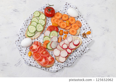 Useful breakfast, fried bread, carrots and cucumbers, tomatoes and radishes, eggs, green sandwiches, fermented foods, the concept of a healthy diet and weight loss, diet mini-sandwiches on a light 125632062