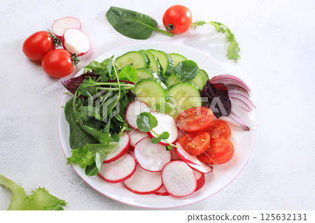 Green vegetable salad with cherry tomatoes, cucumber, radish and fresh arugula, detox diet. Healthy natural breakfast for weight loss, cholesterol and GMO free, selective focus, place for text, 125632131