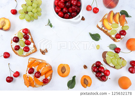 Diet fruit bruschetta with cottage cheese, peaches, grapes and cherries, a healthy breakfast with ingredients. The concept of healthy and natural food, lifestyle, flat lay, place for text 125632178