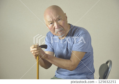 An elderly man with poor leg stability using a walking stick indoors 125632251