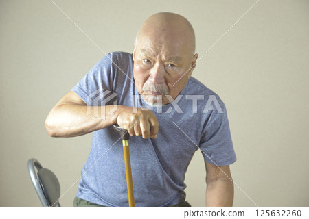 An elderly man with poor leg stability using a walking stick indoors 125632260