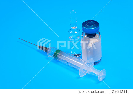 Close-up medical syringe and vials with medicine for injection on blue background Close-up medical syringe and vials with medicine for injection on blue background 125632313