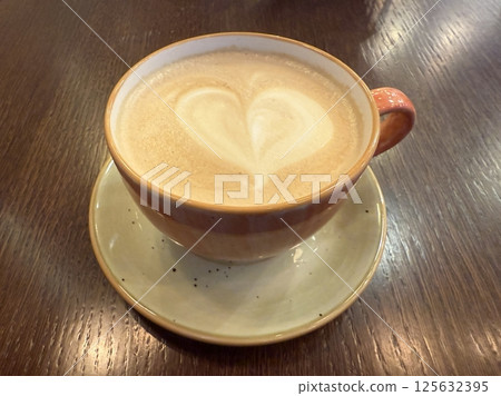 Hot latte art coffee with colored cream on wooden table Hot latte art coffee with colored cream on wooden table 125632395