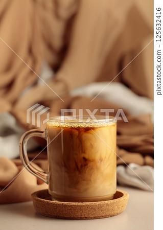 Glass cup of latte on a beige background. 125632416