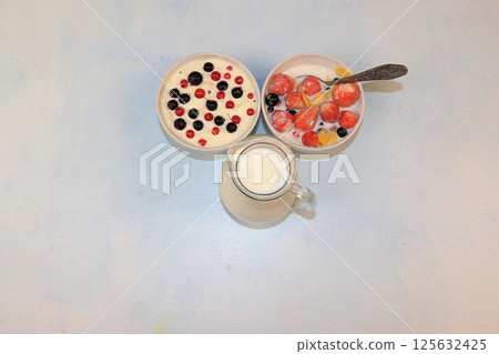 Strawberry yogurt, milk and ripe berries of currants and strawberries on a light background. Delicious healthy breakfast of yogurt and strawberries with copy space, top view, selective focus Strawberry yogurt, milk and ripe berries of currants and strawberries on a light background. Delicious healthy breakfast of yogurt and strawberries with copy space, top view, selective focus 125632425