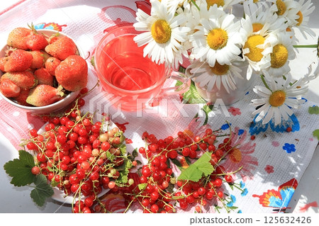 Juicy fresh strawberries and red currants on a sunny window, top view, selective focus. Healthy eating concept, perfect morning for a good mood. 125632426
