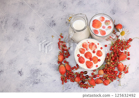 Strawberry yogurt, milk and ripe currant berries and strawberries on a light background, the concept of a healthy diet. Delicious healthy breakfast of yogurt and strawberries with copy space, top 125632492