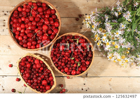 Summer cherry berries in baskets on a wooden background with daisies,wild flowers, harvesting in the village, the concept of healthy natural food, breakfast with ingredients, shop advertising, cafe Summer cherry berries in baskets on a wooden background with daisies,wild flowers, harvesting in the village, the concept of healthy natural food, breakfast with ingredients, shop advertising, cafe 125632497