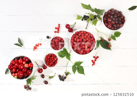 Summer fresh cherries, currants and raspberries on a light wooden background with leaves, banner and shop advertisement, village harvest, healthy natural food concept, breakfast with ingredients, cafe 125632510
