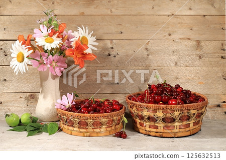 Summer cherry berries in baskets on a wooden background with daisies,wild flowers, harvesting in the village, the concept of healthy natural food, breakfast with ingredients, shop advertising, cafe 125632513