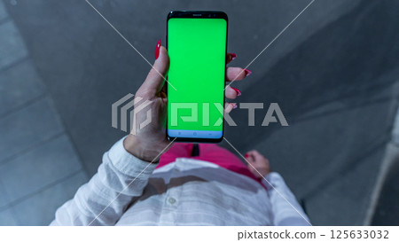Female teen girl with red nails using smartphone with green screen staying outdoors. Female teen girl with red nails using smartphone with green screen staying outdoors. 125633032