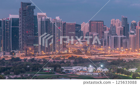 Jumeirah lake towers and Dubai marina skyscrapers and golf course night to day timelapse, Dubai, United Arab Emirates 125633088