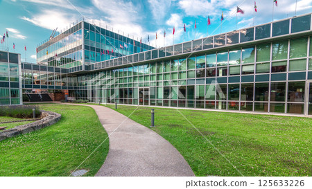 Modern low rise glass office building in business district and green lawn in inner yard timelapse hyperlapse 125633226