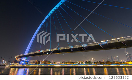 Futuristic Pedestrian Bridge over the Dubai Water Canal Illuminated at Night timelapse hyperlapse, UAE. Futuristic Pedestrian Bridge over the Dubai Water Canal Illuminated at Night timelapse hyperlapse, UAE. 125633332
