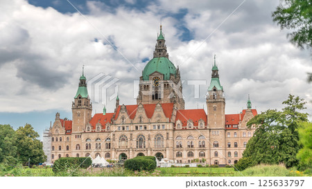 Hyperlapse of Hanover's New Town Hall, a landmark castle-like structure surrounded by park and lake under a cloudy sky. Germany 125633797