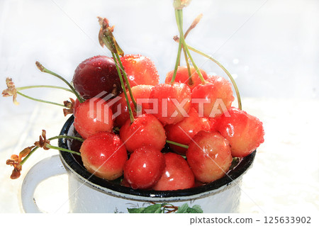 Cherries in drops in an old mug on a white wet table, selective focus, tasty summer sweet cherry close-up Cherries in drops in an old mug on a white wet table, selective focus, tasty summer sweet cherry close-up 125633902
